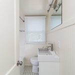 a modernized bathroom with white walls and white rectangular vanity