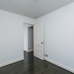 a bedroom door opened with white walls and full wood floor