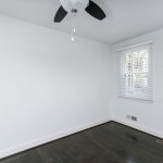 two windows, a white wall and ceiling fan