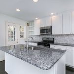 a kitchen with new appliances dark floors and granite counters