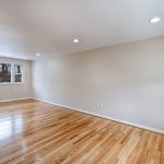 a hardwood floored room with beige walls and inset lighting