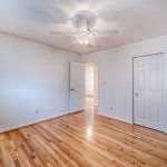 a white, wood floored room with ceiling fan