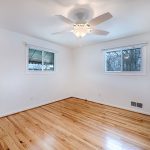 a hardwood floored room with freshly painted white walls